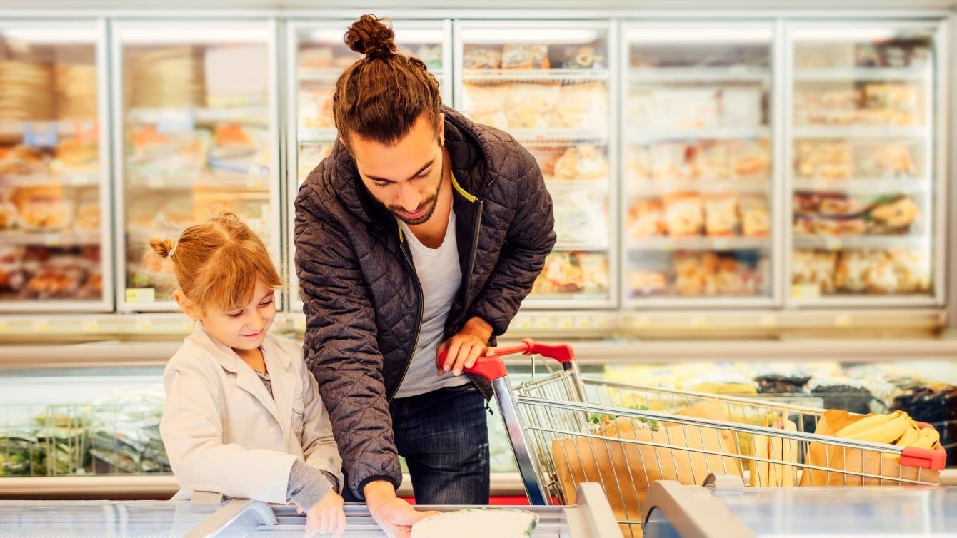 Father and child pick food items from grocery store freezer