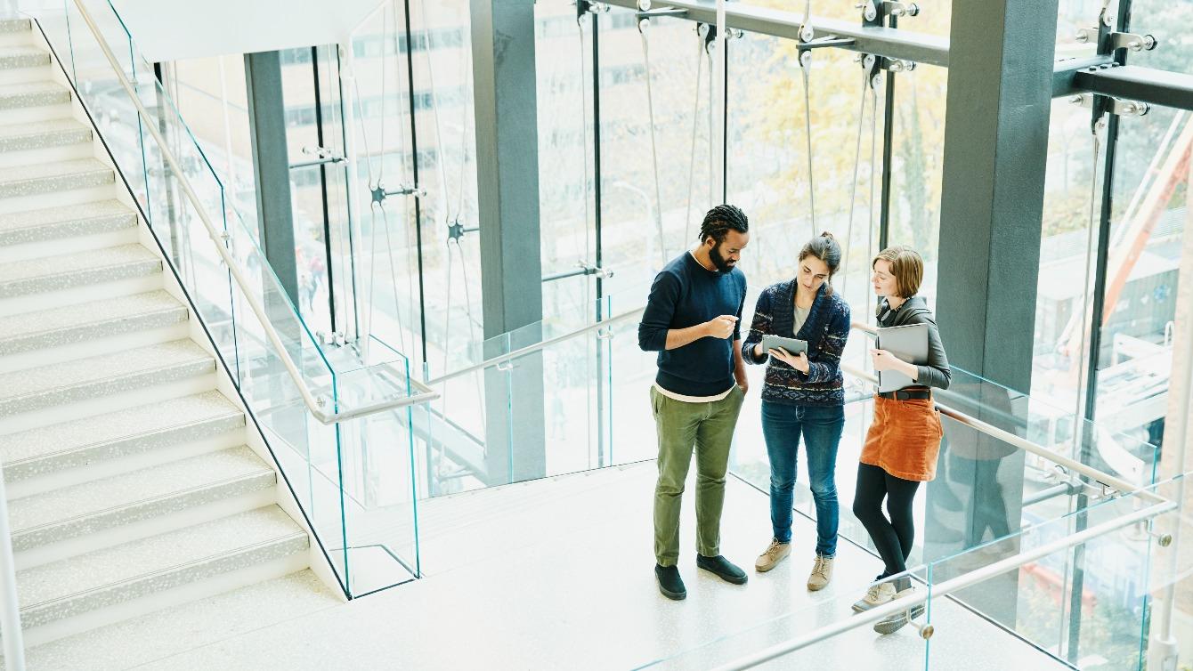 Group of people have a stand up conversation in a windowed office stairwell