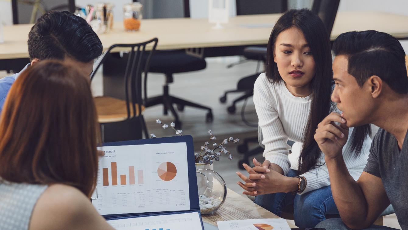 Groupof coworkers discussing the company debt data on a laptop