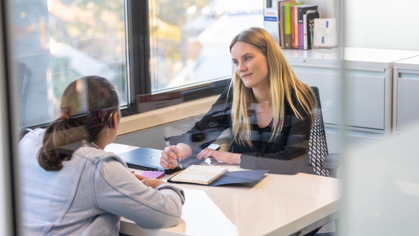 Two women have a discussion in a bright office