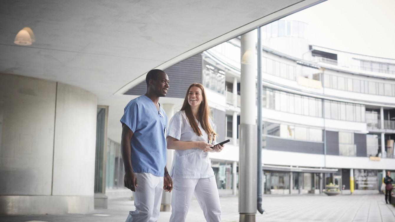 Two medical professionals having a conversation while walking outside a hospital